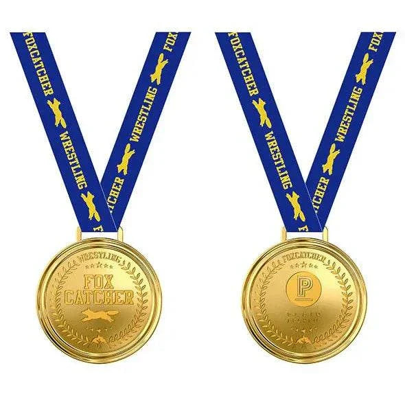 Gold-colored Foxcatcher Deluxe Box commemorative medal with blue "Foxcatcher Wrestling" lanyard