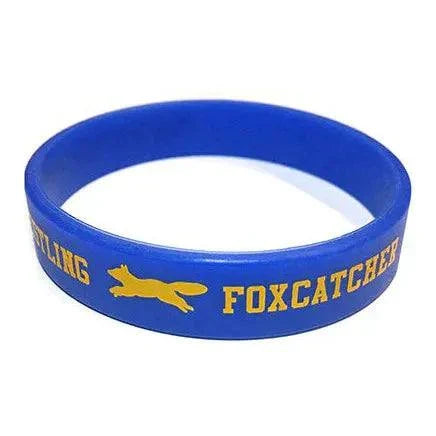 Blue silicone wristband with gold Foxcatcher logo from Foxcatcher Deluxe Box Blu-ray Steelbook set