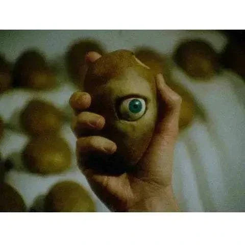 Hand holding a disembodied head with a single blue eye, representing the film Disembodied in Bleeding Skull 4K UHD and Blu-Ray edition.
