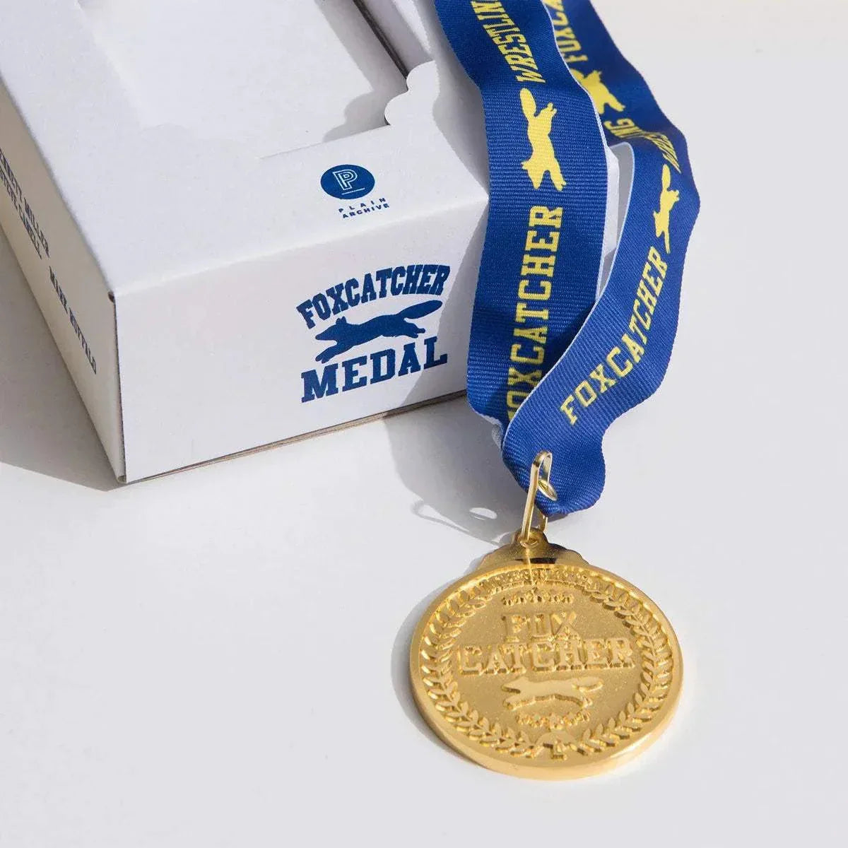 Foxcatcher Deluxe Box Blu-ray Steelbook with gold medal and blue lanyard embossed with "Foxcatcher"