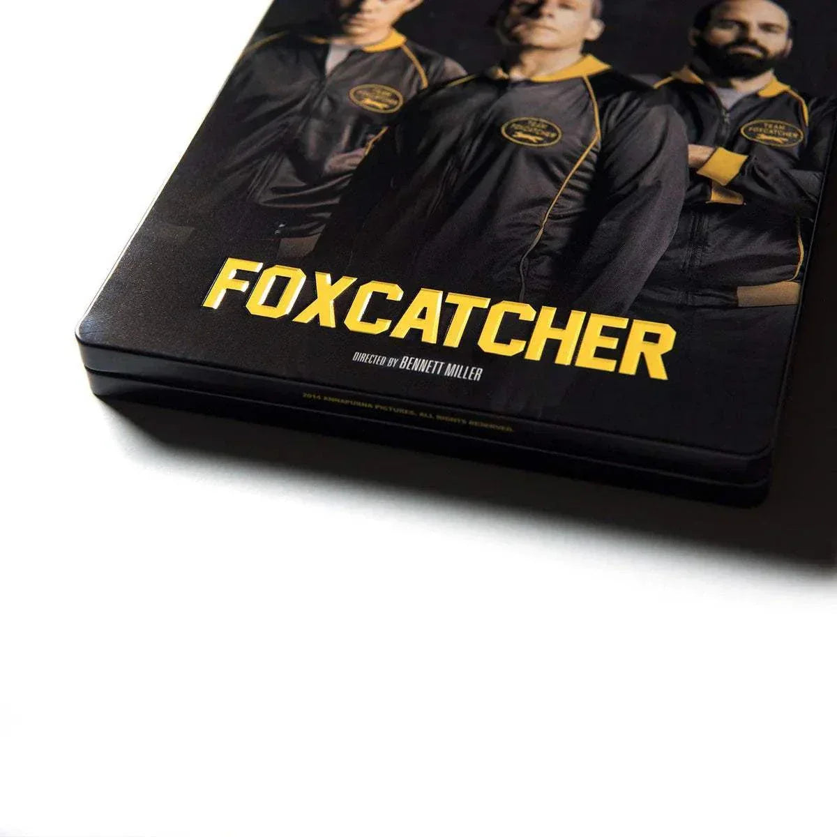Foxcatcher Deluxe Box Blu-ray Steelbook featuring cast image and yellow title text on black background