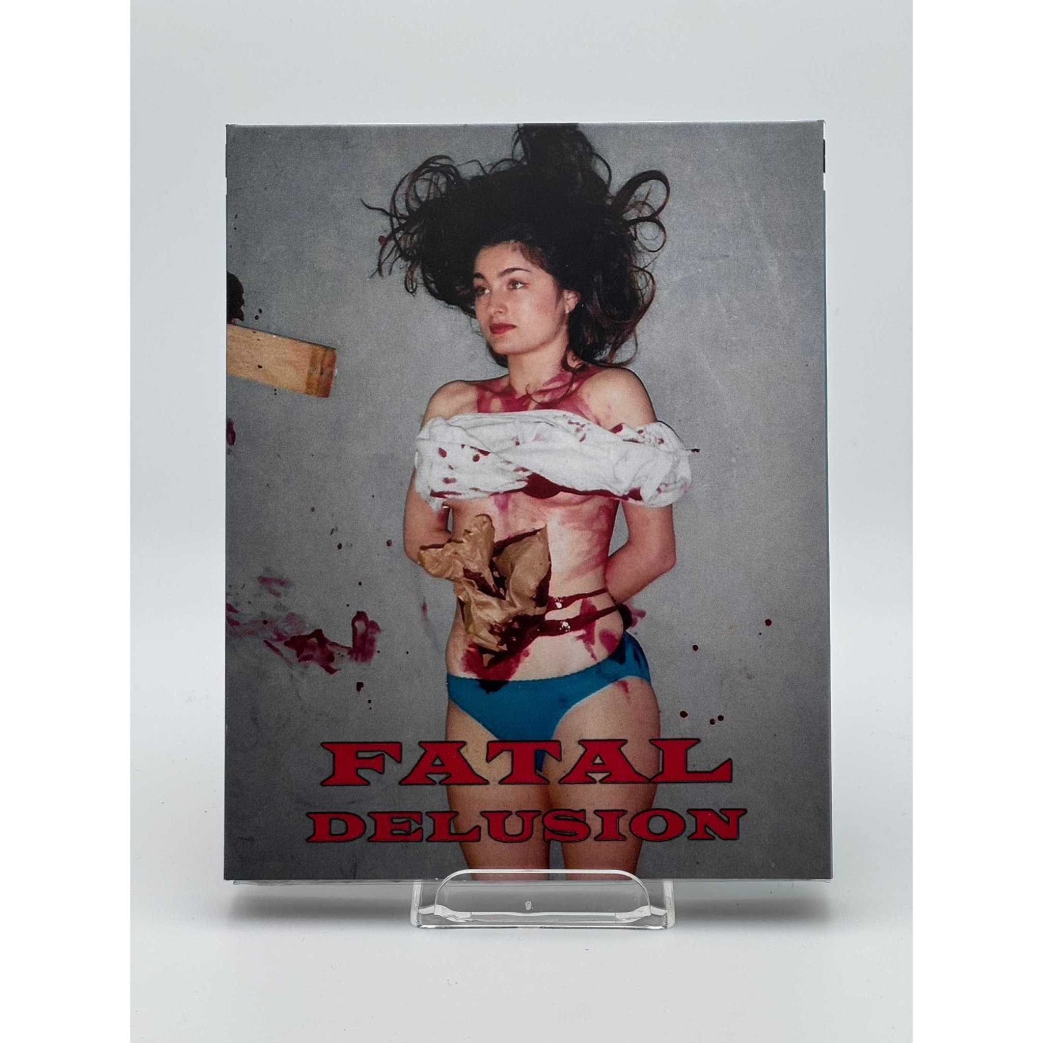 Saturn's Core Fatal Delusion Blu-Ray cover featuring a bloodied woman in blue underwear and a torn white shirt against a gray background